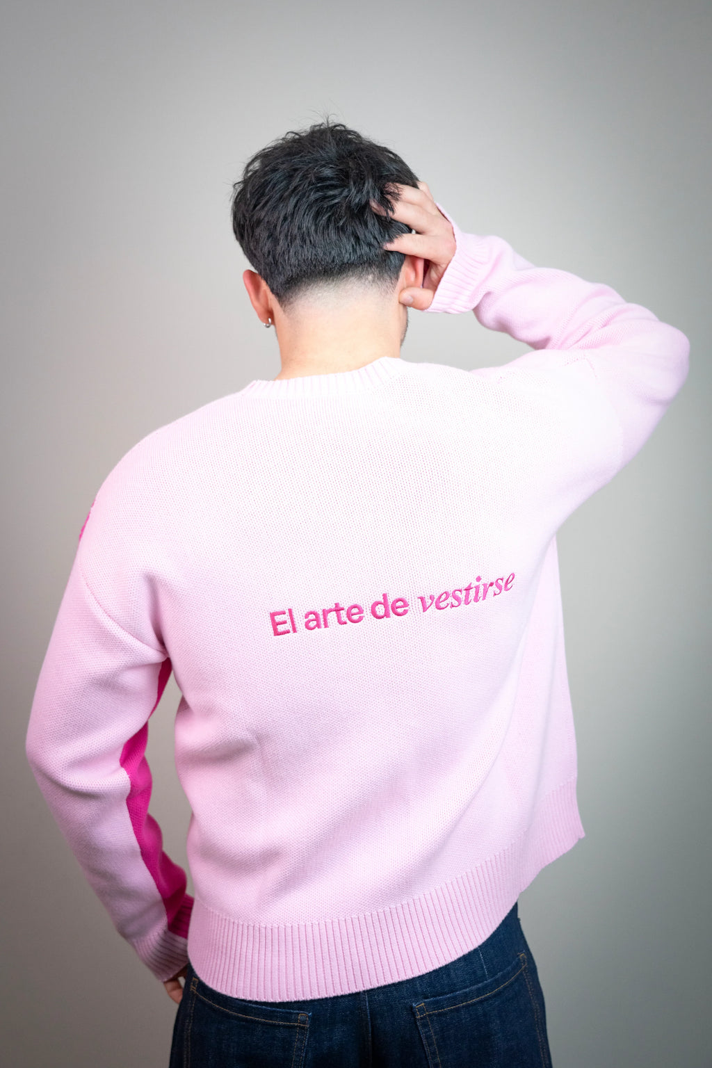 Persona de espaldas con suéter rosa, frase 'El arte de vestirse', moda urbana elegante