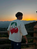 Chico con camiseta blanca de cerezas rojas al atardecer en paisaje de montaña